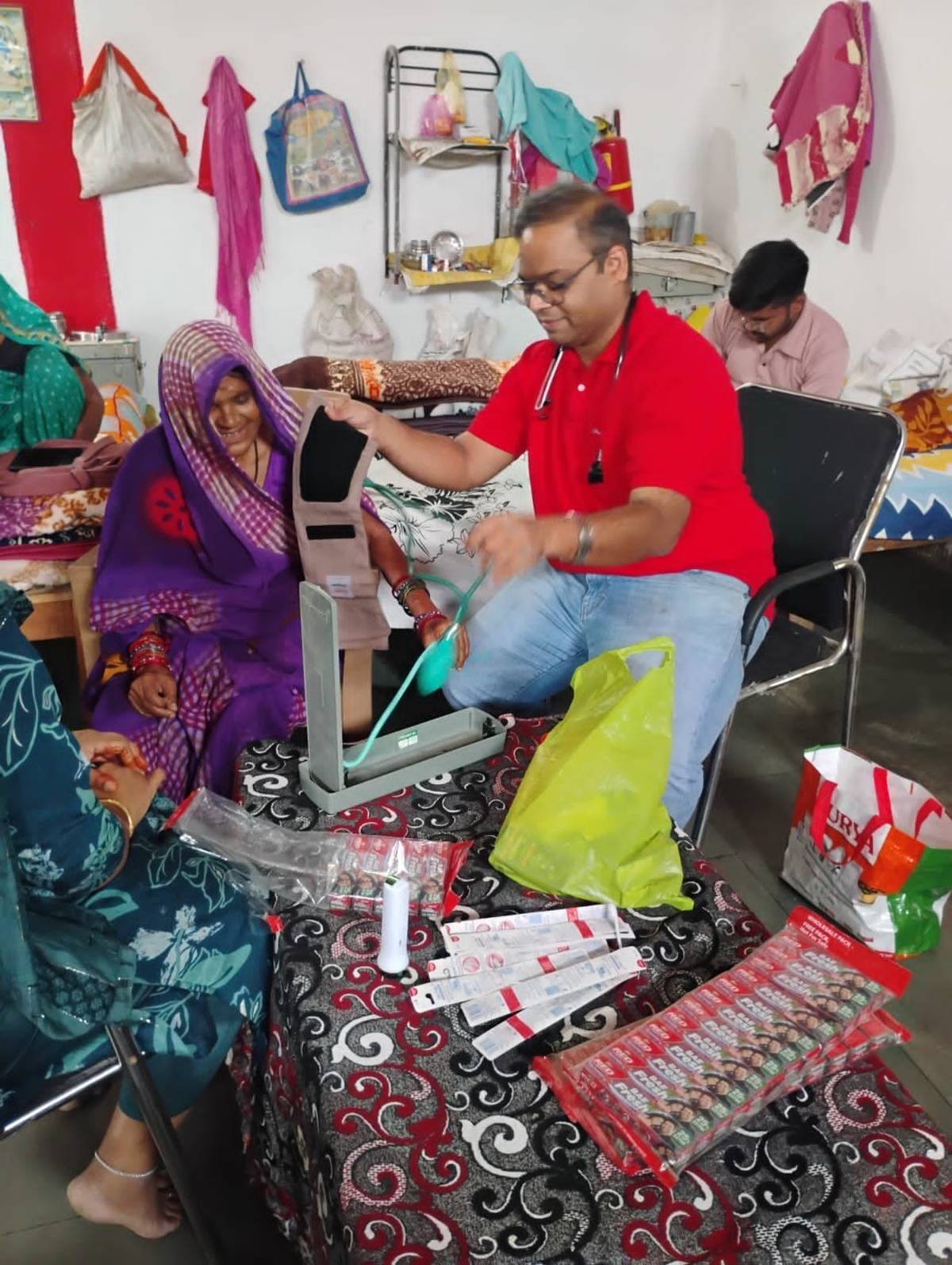 Doctor checking blood pressure of a senior citizen at a village health camp